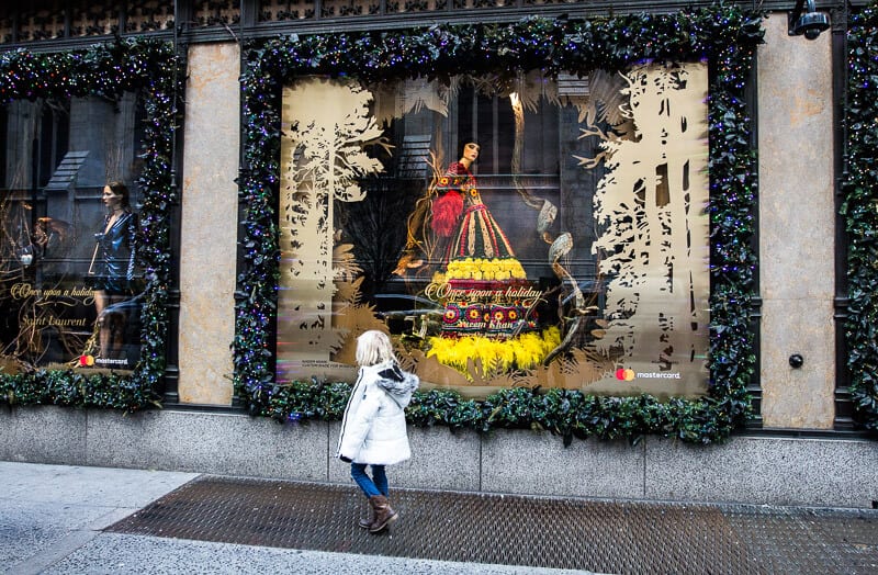 young girl looking at Saks 5th avenue window displays