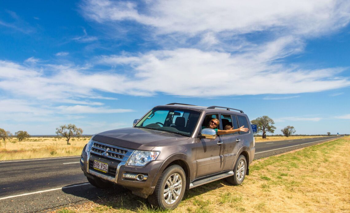 lady haning out of car in the outback