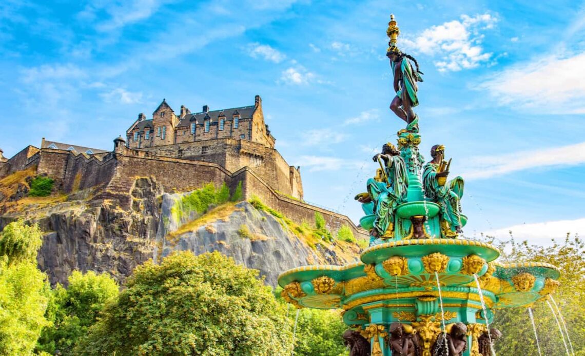 A historic old fountain near the towering Castle in Edinburgh, Scotland on a sunny day