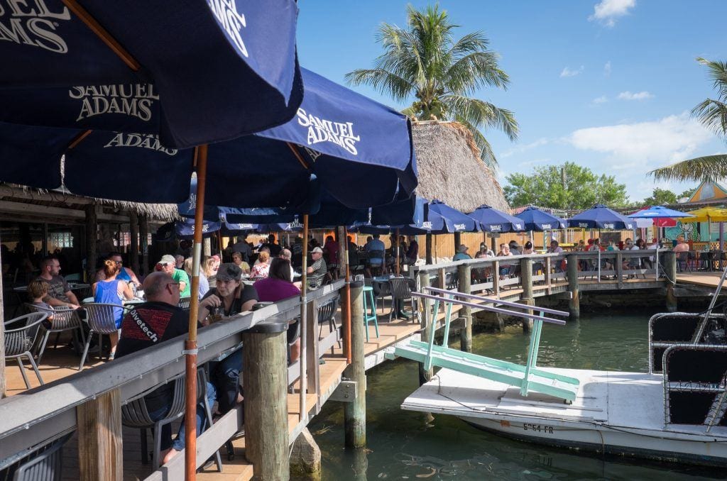 An outdoor restaurant in the Florida Keys, people sitting out o the deck.