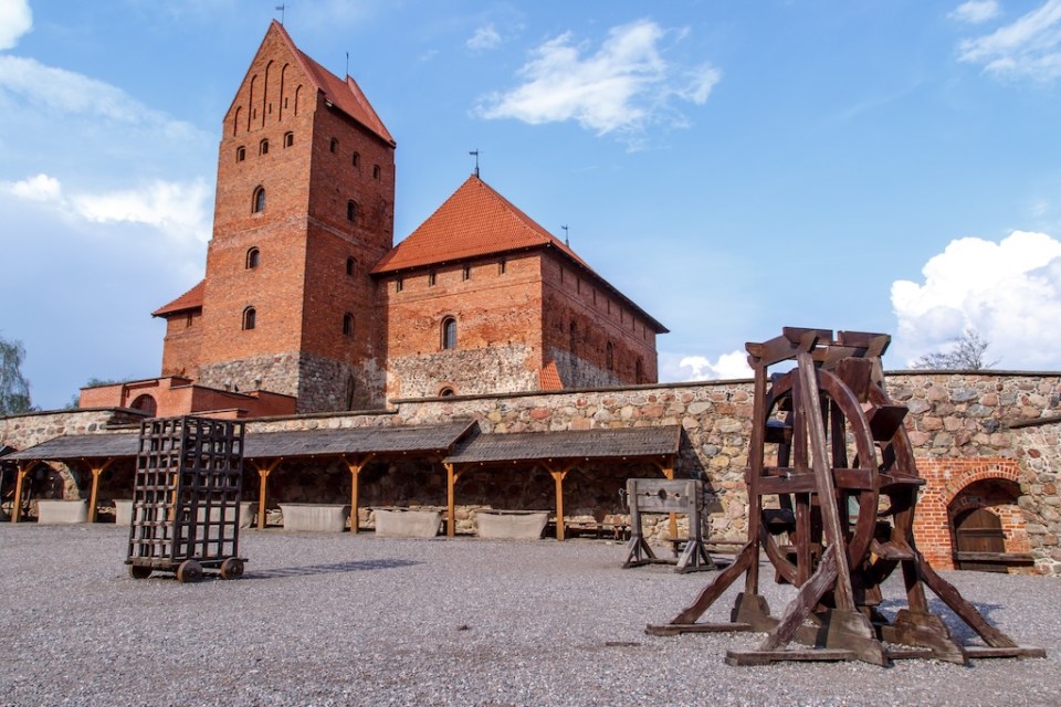 View of Trakai Castle and buildings of it in Lithuania with high brown brickwalls, on cloudy sky background.