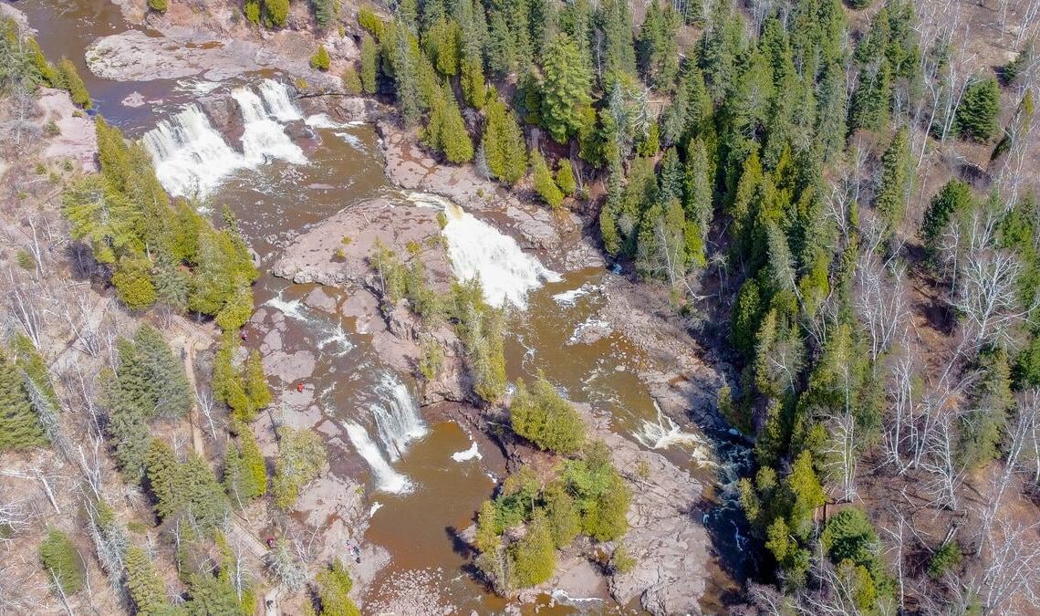 Aerial photograph of Gooseberry Falls with cascading water, evergreen trees, and visitors at the park, illustrating Minnesota's scenic landscapes.