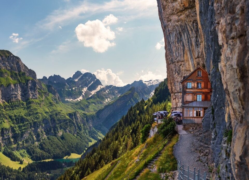 Swiss Alps and a mountain restaurant under the Ascher cliff viewed from mountain Ebenalp in the Appenzell region in Switzerland