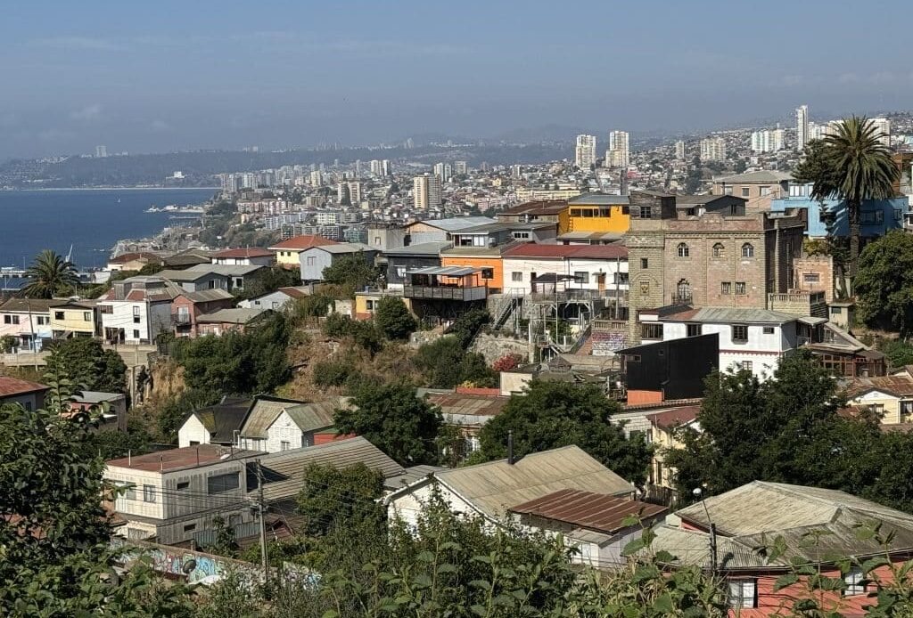 Views of Valparaiso from above, with colorful buildings atop several hills, pushed up against the coastline.
