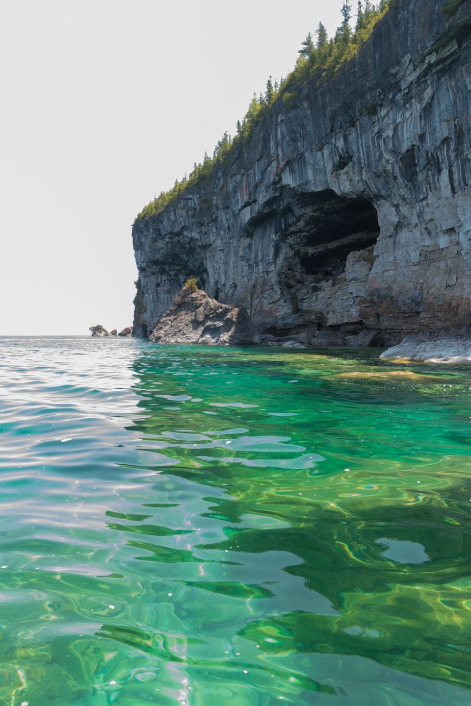 Bright clear aqua green water on Bruce Peninsula. Crystal clear water shows big limestone rocks and cliff