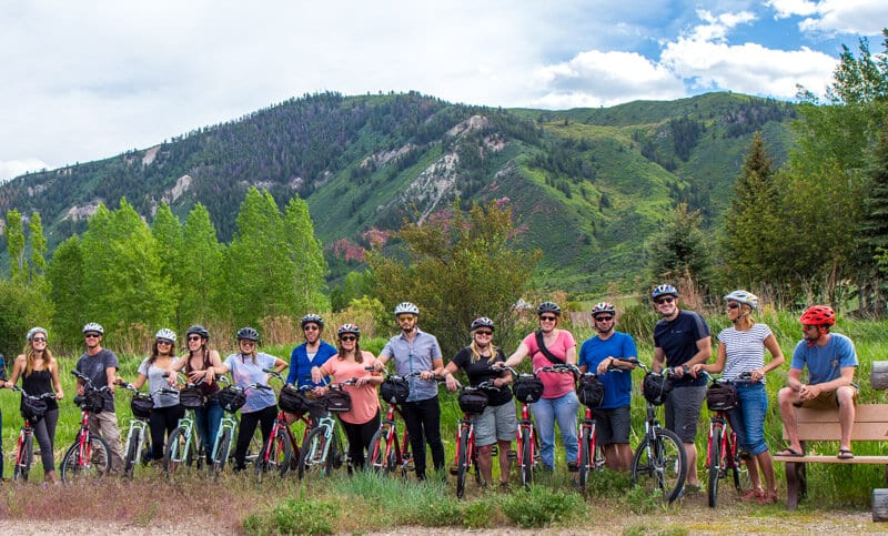 group of people standing next to bikes in front of mountain