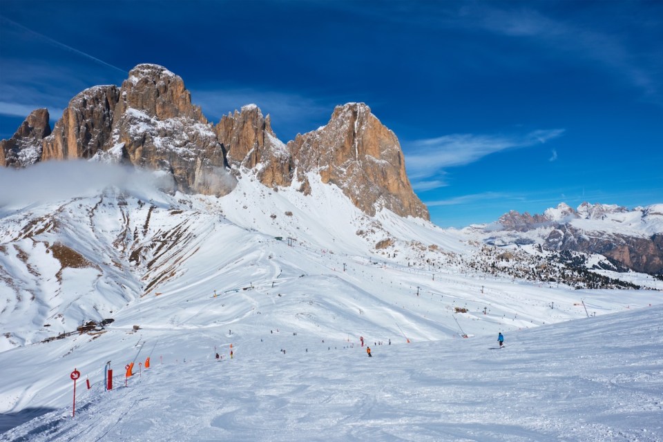 View of a ski resort piste with people skiing in Dolomites in Italy