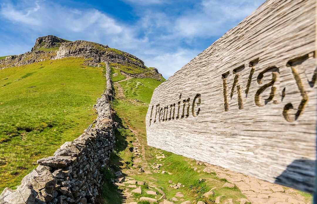 A close-up of a Pennine Way sign pointed up a mountain in the Yorkshire Dales