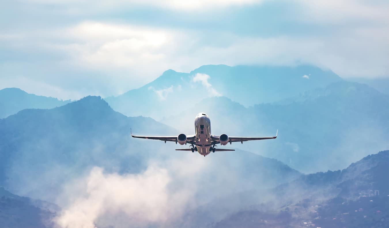 A large commercial jet flying through the bright blue sky as it takes off