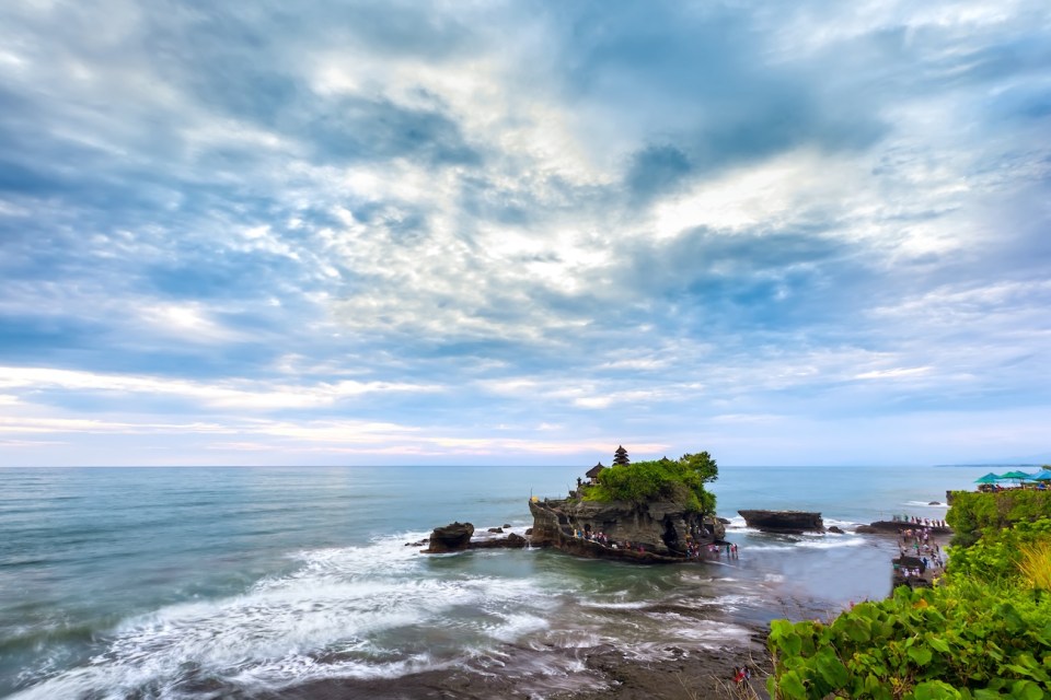 The Pilgrimage Temple of Pura Tanah at sunset, the island with the Indonesian shrine on the ocean, in cloudy weather, the sky in the clouds.