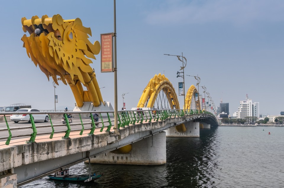 Da Nang, Vietnam - March 10, 2019: Cau Rong or Dragon bridge from east, head, to west, tail under blue sky. Traffic on bridge and Vietnam Television Center building on other side.