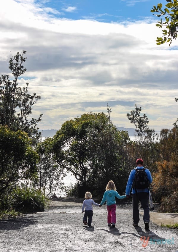 father and two daughters walking on a trail at captain cook lookout