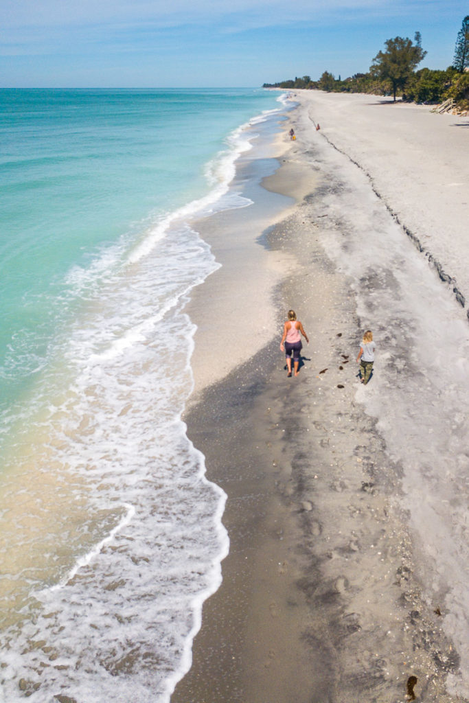 aerial of woman and child walking on englewood beach