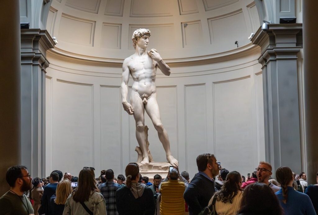The statue of David, surrounded by people taking pictures of it.