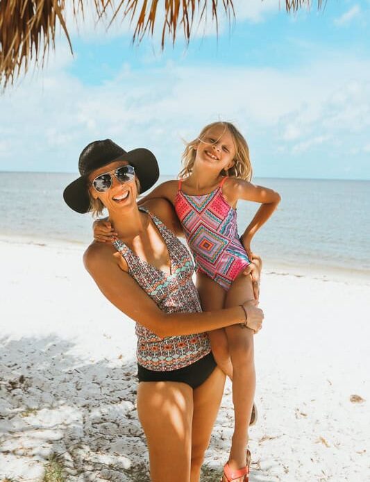 woman and child hugging and laughing on beach