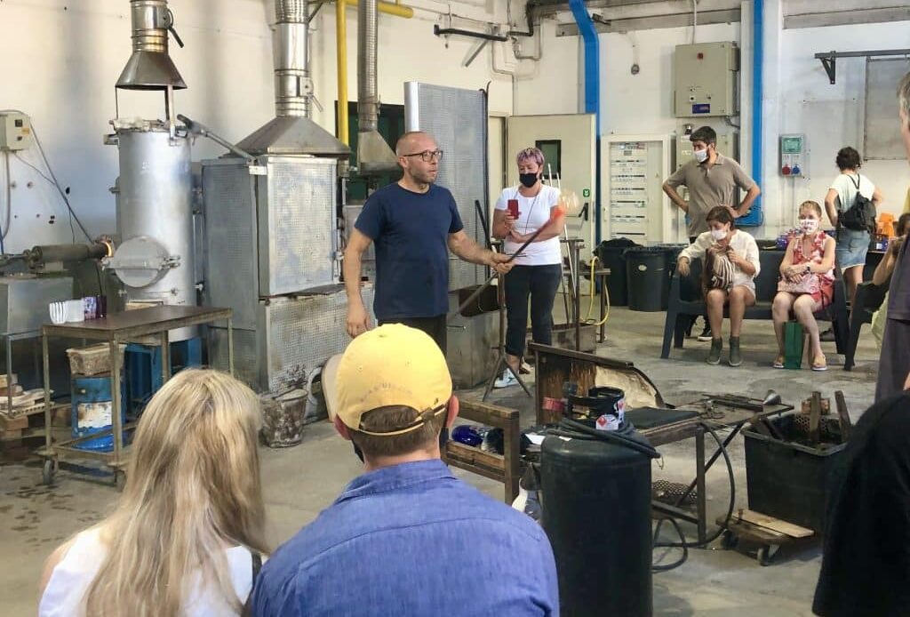 A glassblowing artist demonstrates how to shape glass to an audience.
