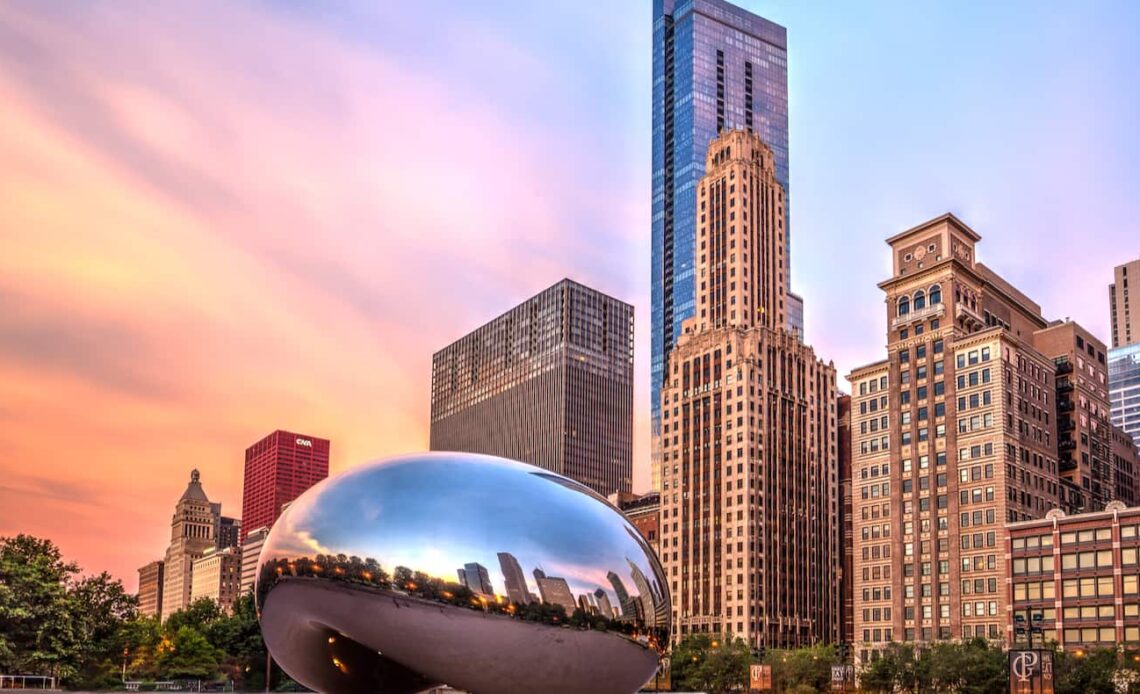 The famous Bean in Chicago at sunset, near the towering downtown of the city