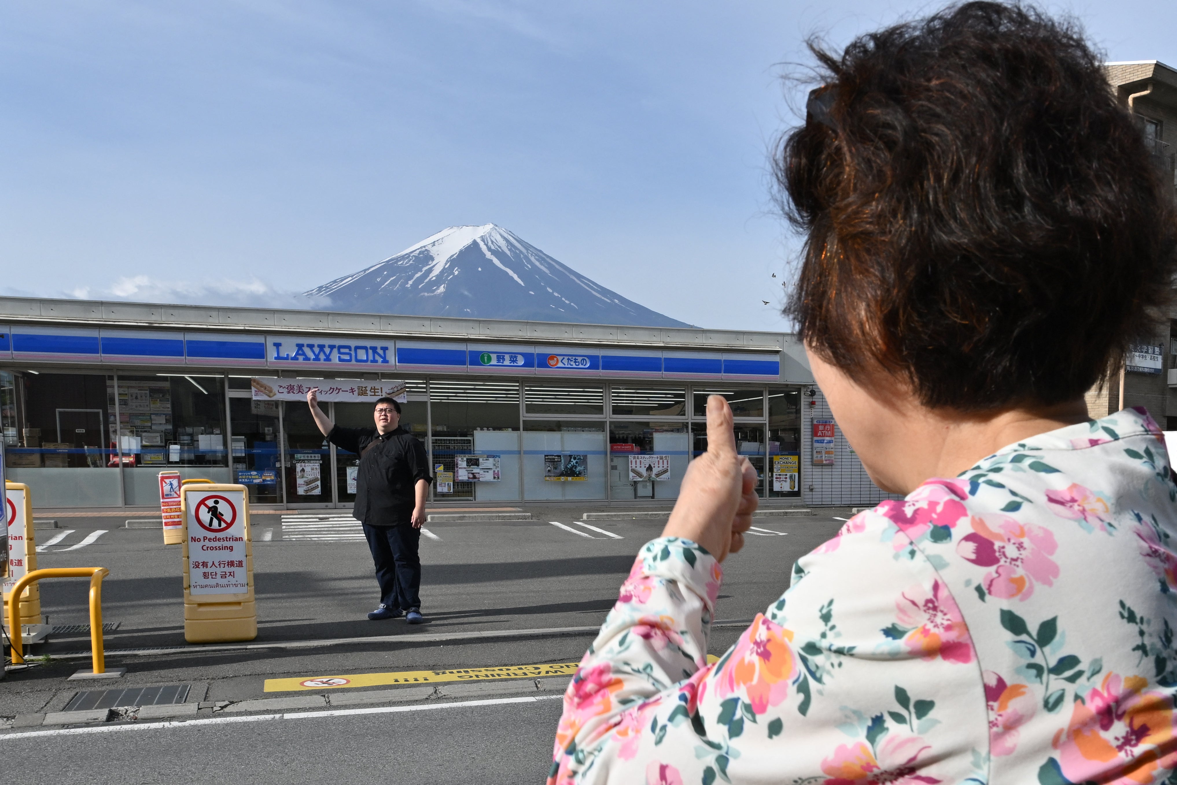 A person takes pictures of Mount Fuji from across the street of a convenience store, hours before the installation of a barrier