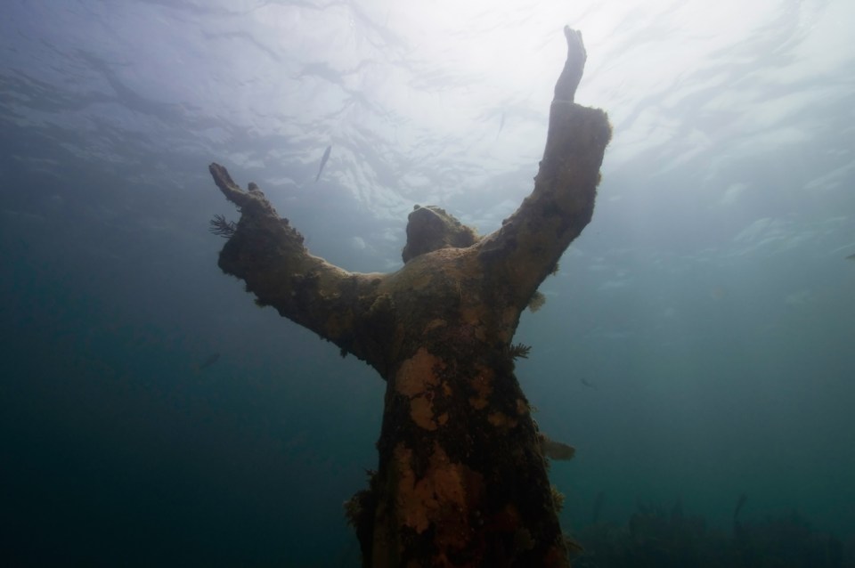 Underwater Religious Enlightenment - Christ of the abyss statue against the water surface, located underwater, about 25 feet deep off Key Largo in Florida. Wide angle, ambiental light.