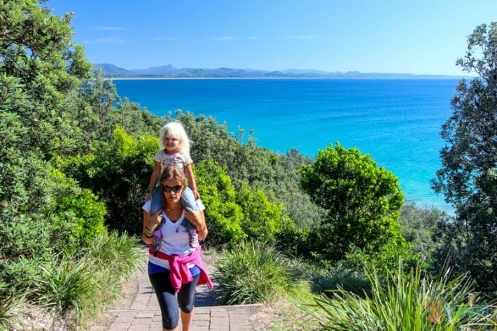 woman walking with child on shoulders up to Byron Bay Lighthouse walk - one of the best short walks in Australia