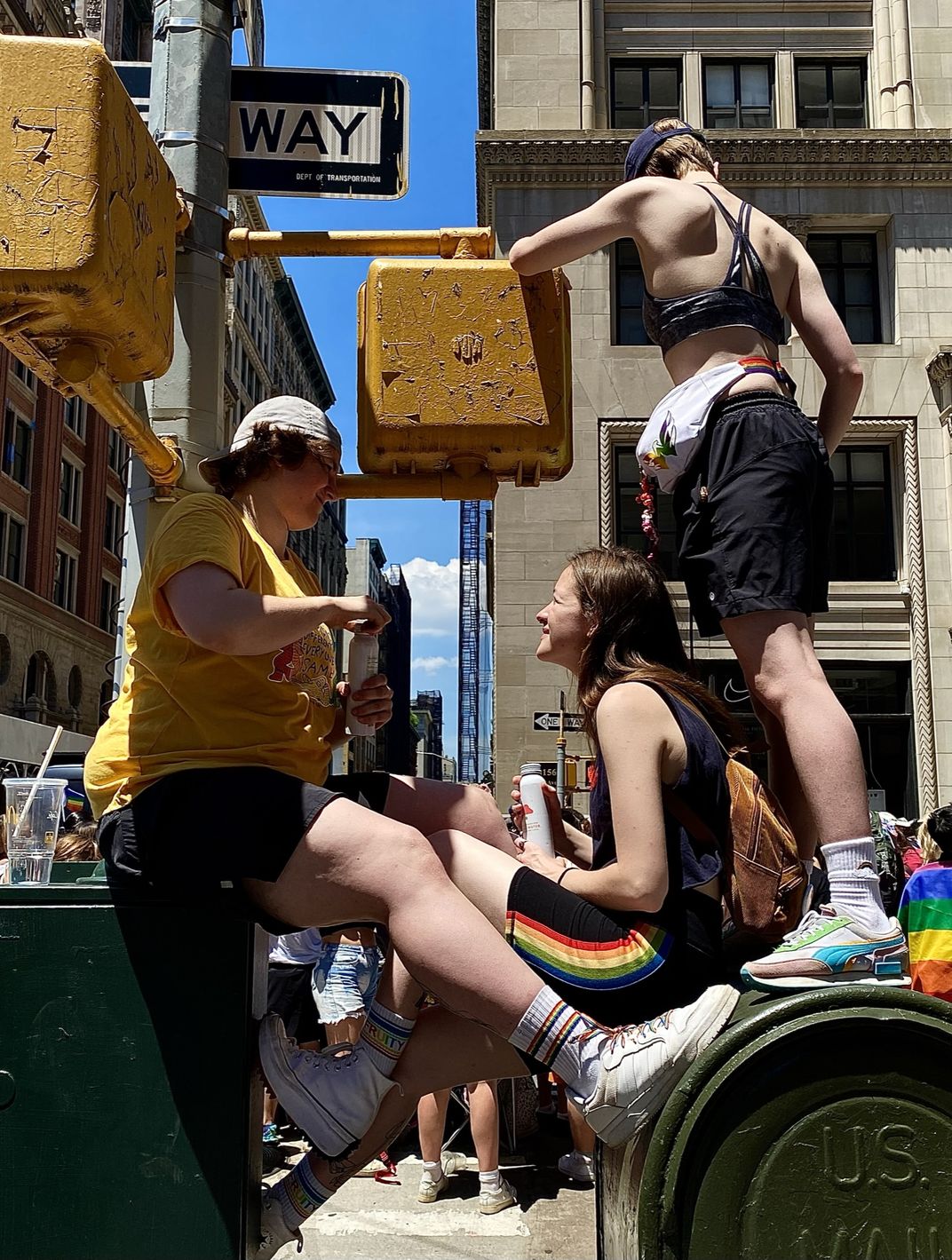 people sit on a mail box during a pride parade