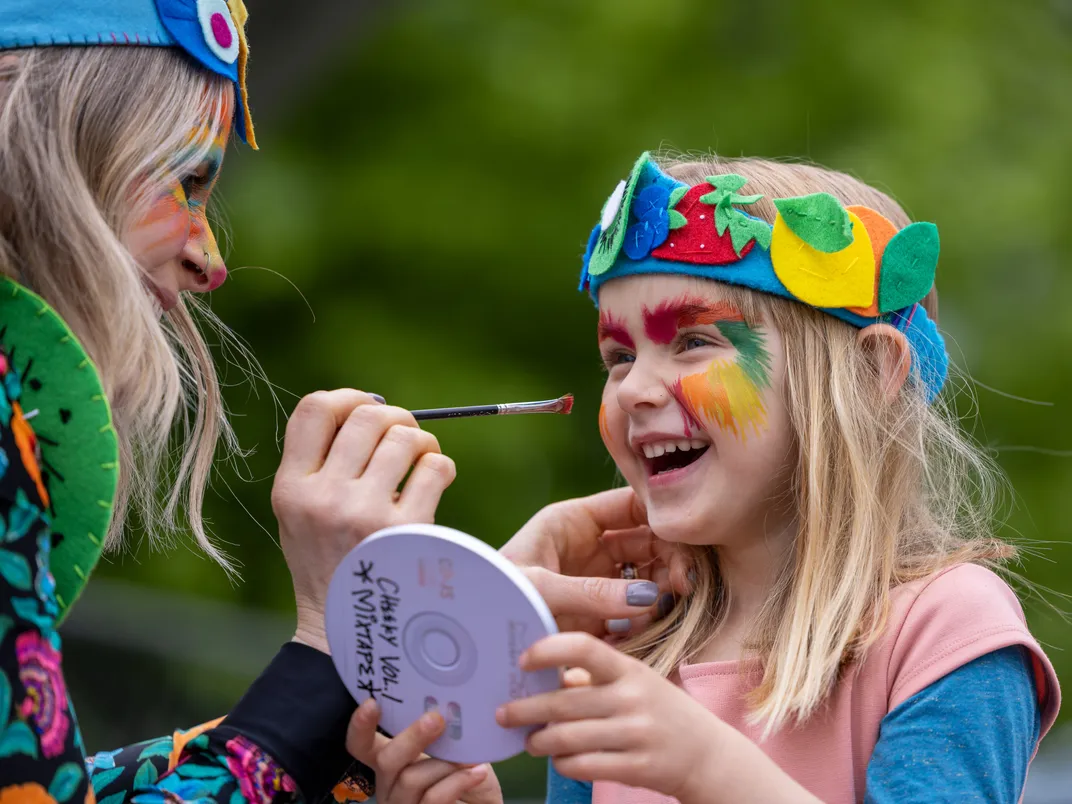 Mother paints daughter's face with paint