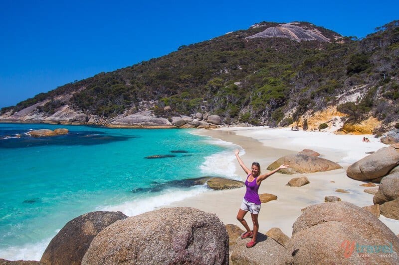 woman standing on a boulder on the beach