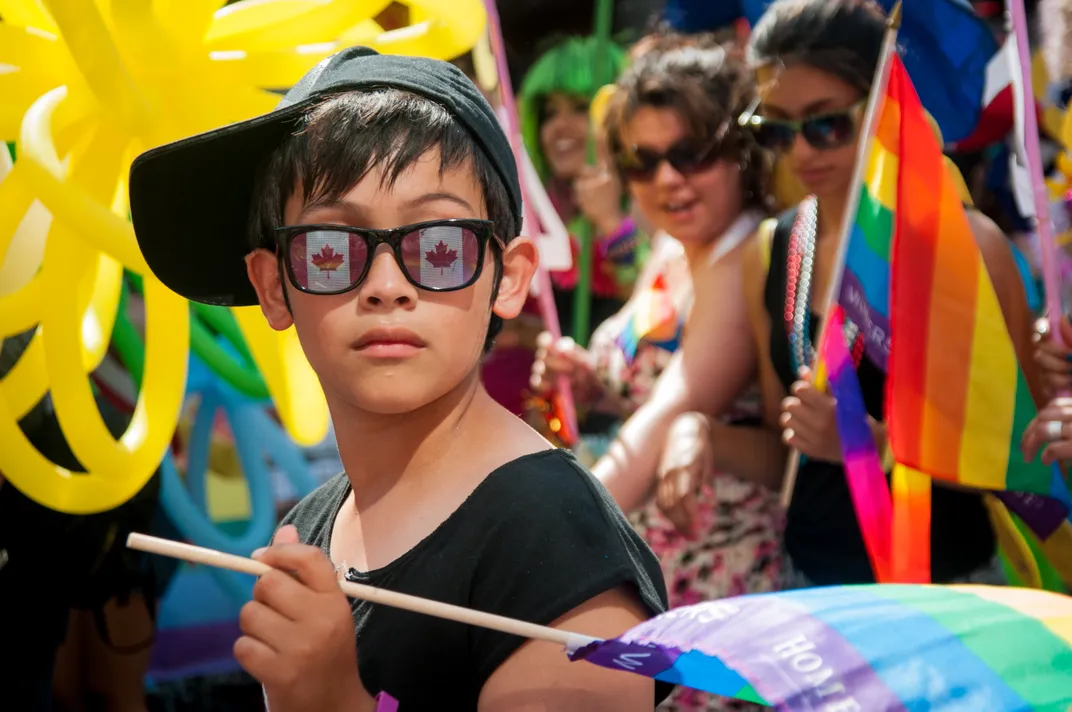 a person wearing sunglasses with the Canadian flag on them during a Pride parade