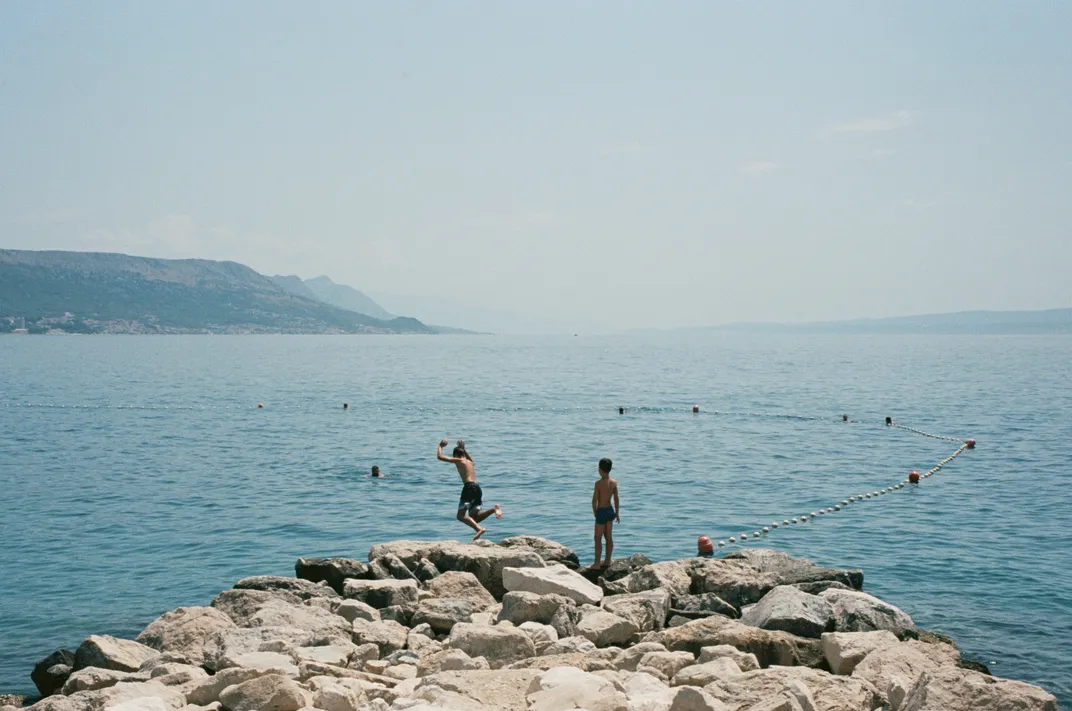 People jumping off cliff in ocean