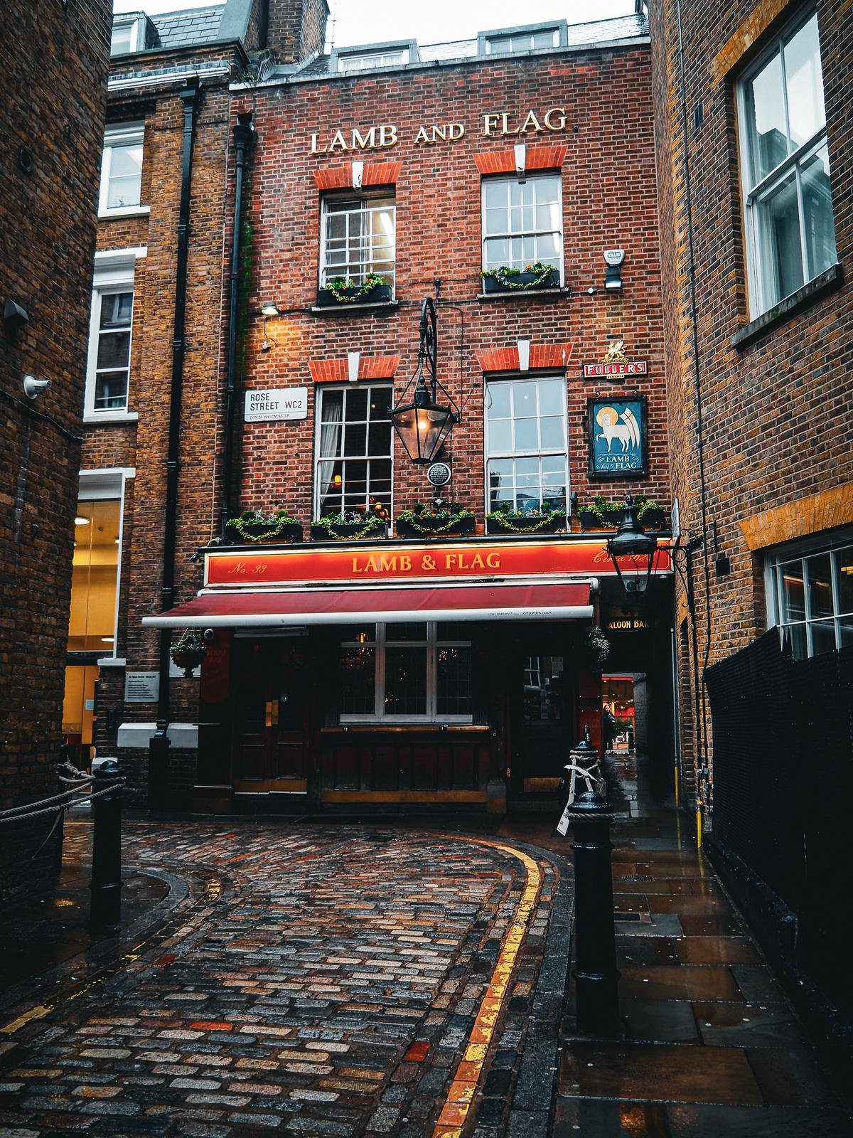 Historic Lamb and Flag Pub on Rose Street, Covent Garden, London - Traditional British Public House on a rainy day in vibrant red facade.