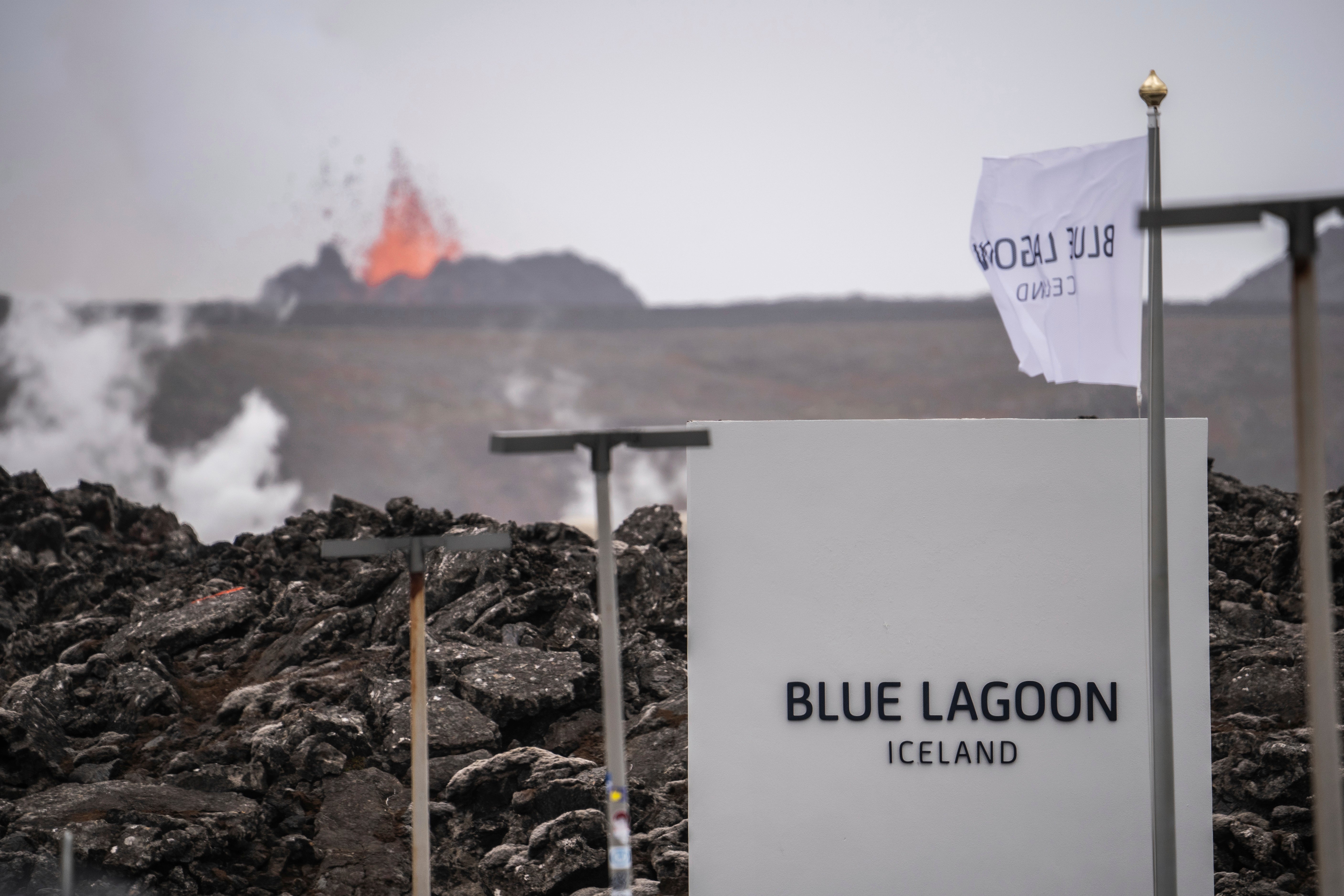The entrance of the Blue Lagoon as the volcano erupts in the background in Grindavik, Iceland, Sunday, June 2, 2024