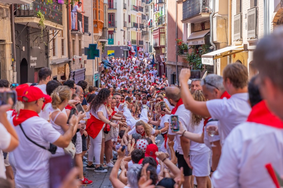 People celebrate San Fermin festival in traditional white abd red clothing with red necktie, Pamplona, Navarra, Spain.