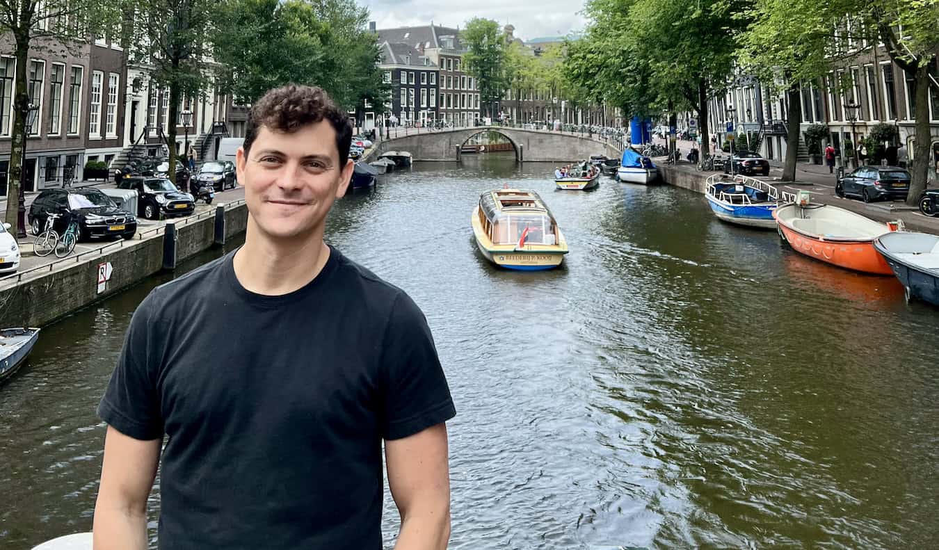 Nomadic Matt posing for a photo near the canal in Amsterdam, Netherlands