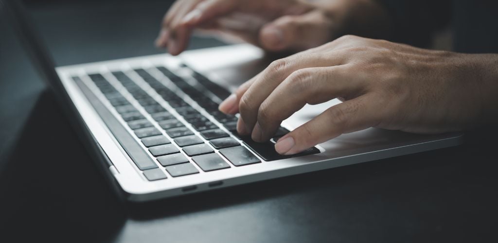 hands typing on laptop keyboard