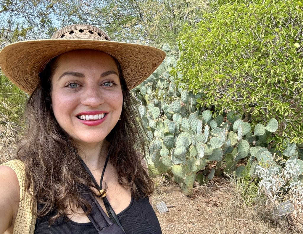 Kate in a sun hat standing in front of a cactus garden.