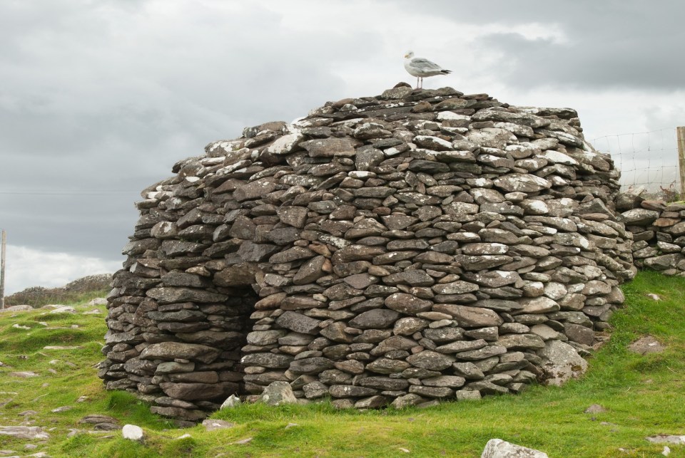 An ancient stone beehive hut in scenic Ireland.