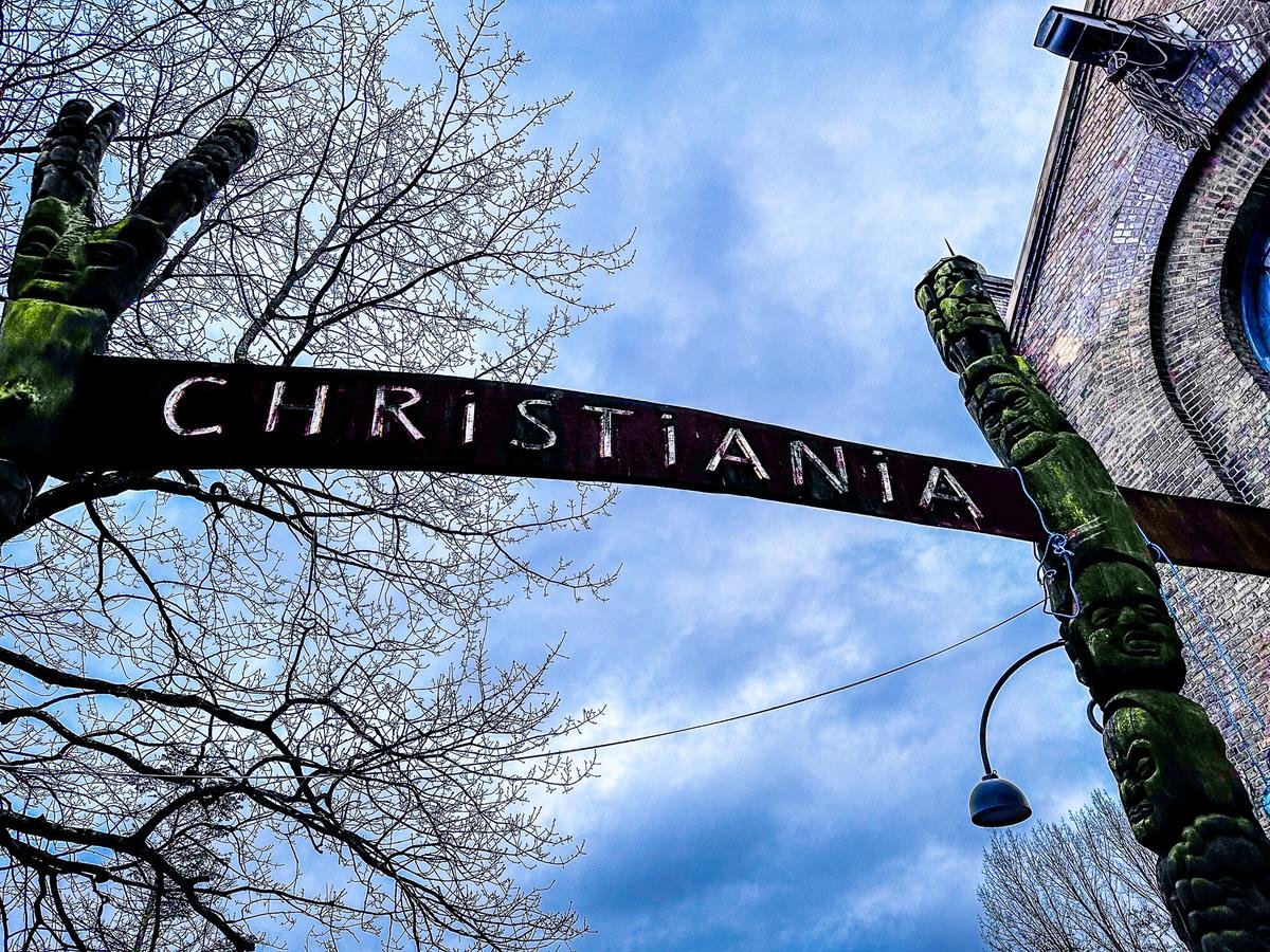 Iconic Christiania Entrance Sign and Sculpture Against Blue Sky in Copenhagen, Denmark