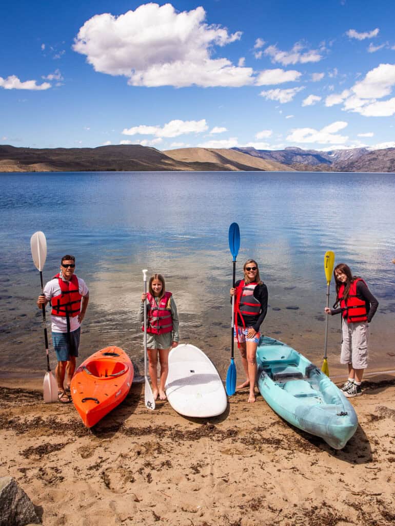 family standing beside paddleboards beside lake