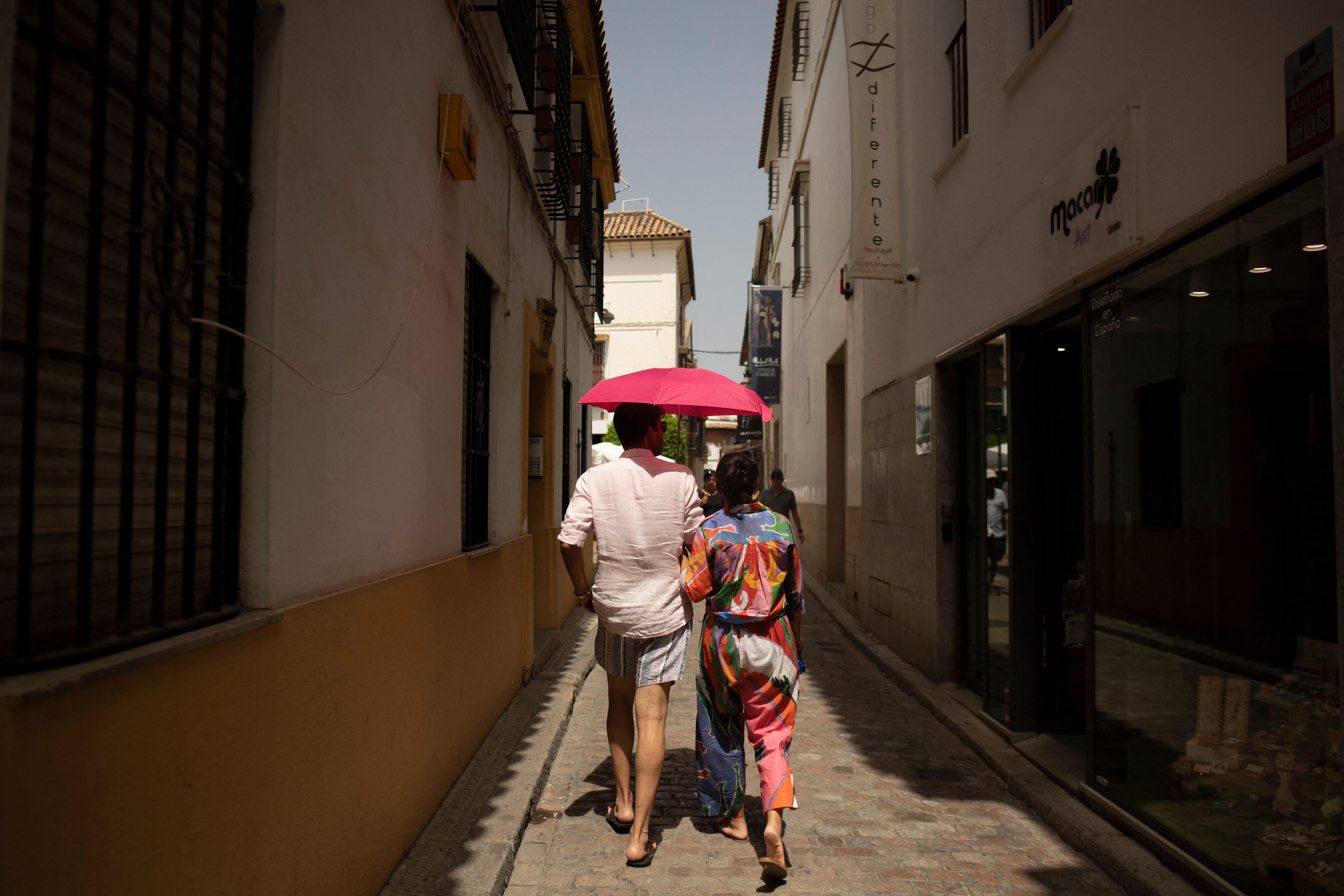 Tourists protect themselves from the sun using an umbrella during a heatwave in Cordoba in Cordoba