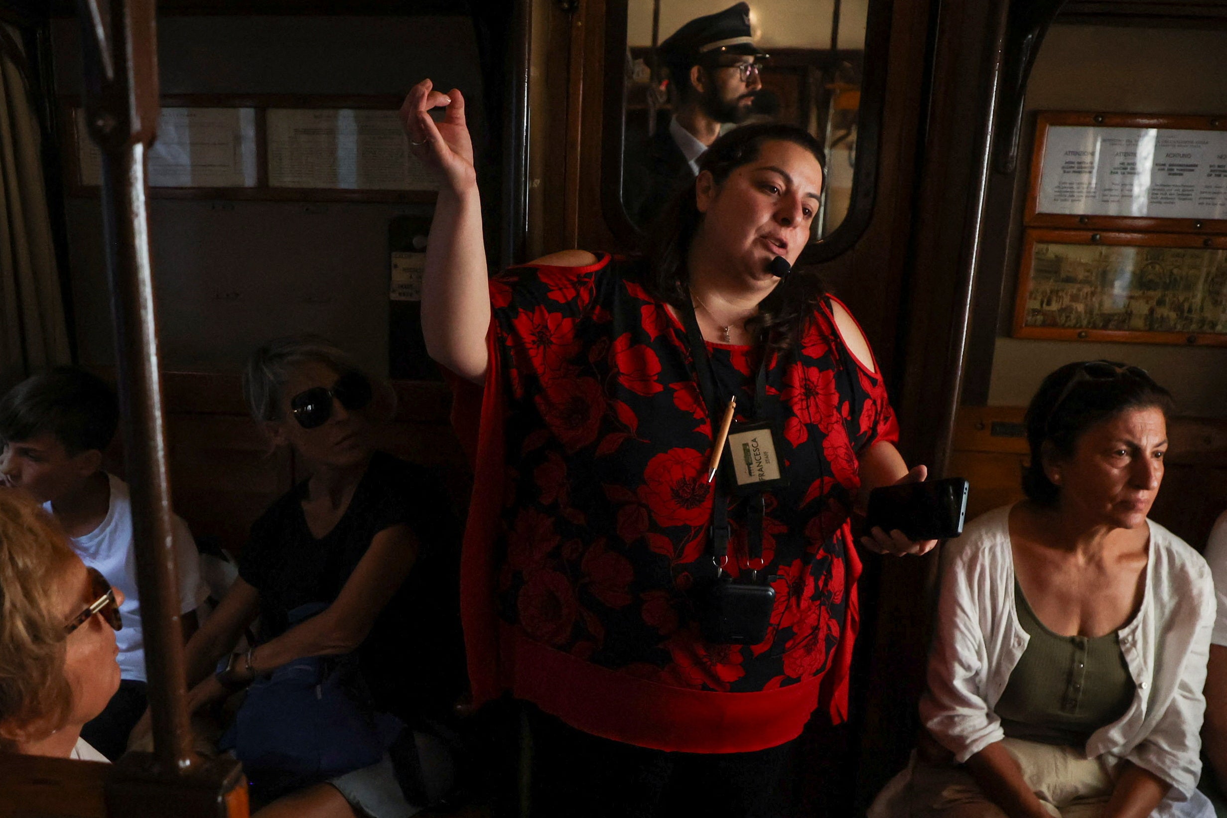 A tourist guide speaks to passengers on board a vintage train travelling from Sulmona to Palena