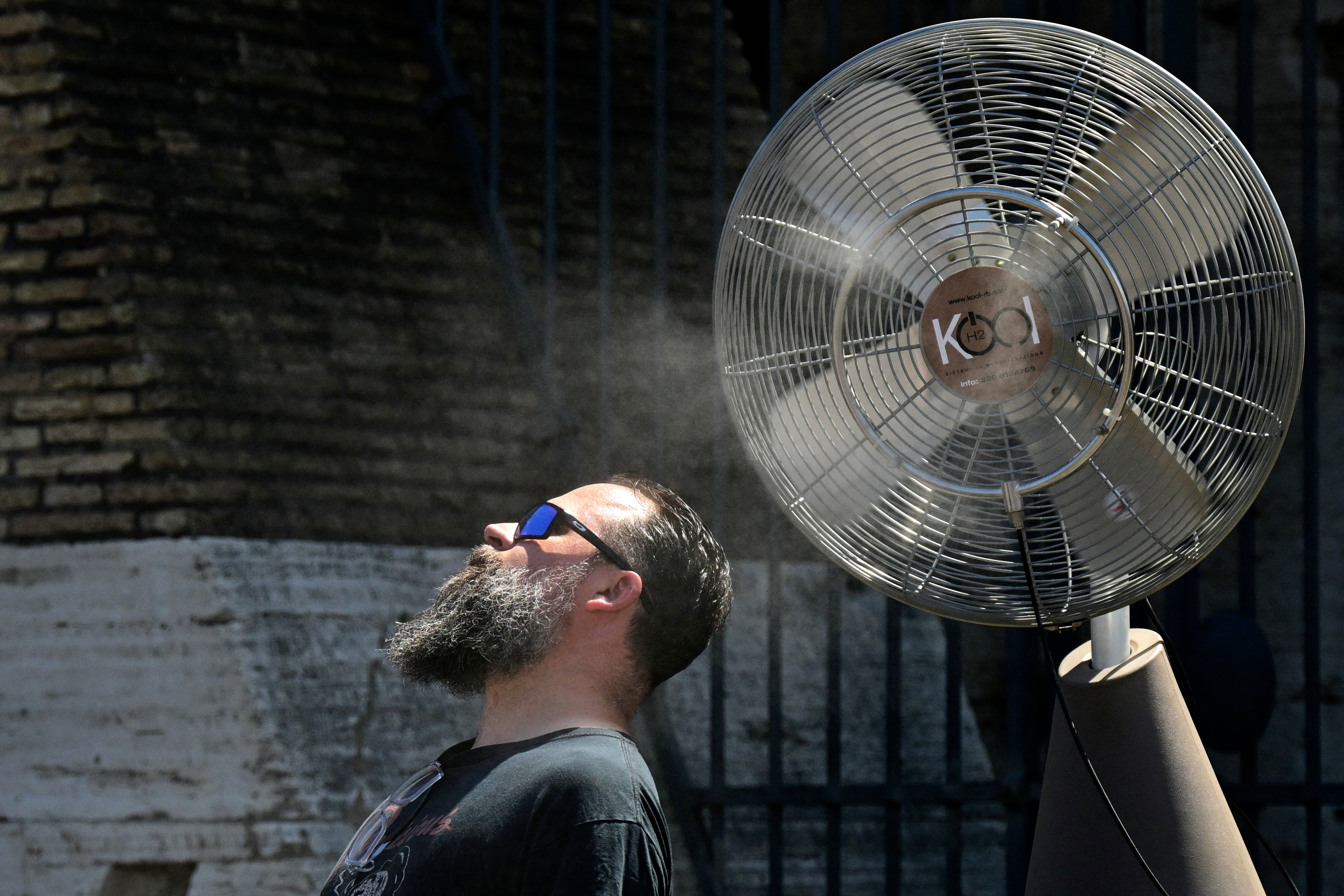 A fan sprays water along the gates of the Colosseum to refresh tourists on July 11, 2024 in Rome where temperatures reach 38 degrees celsius