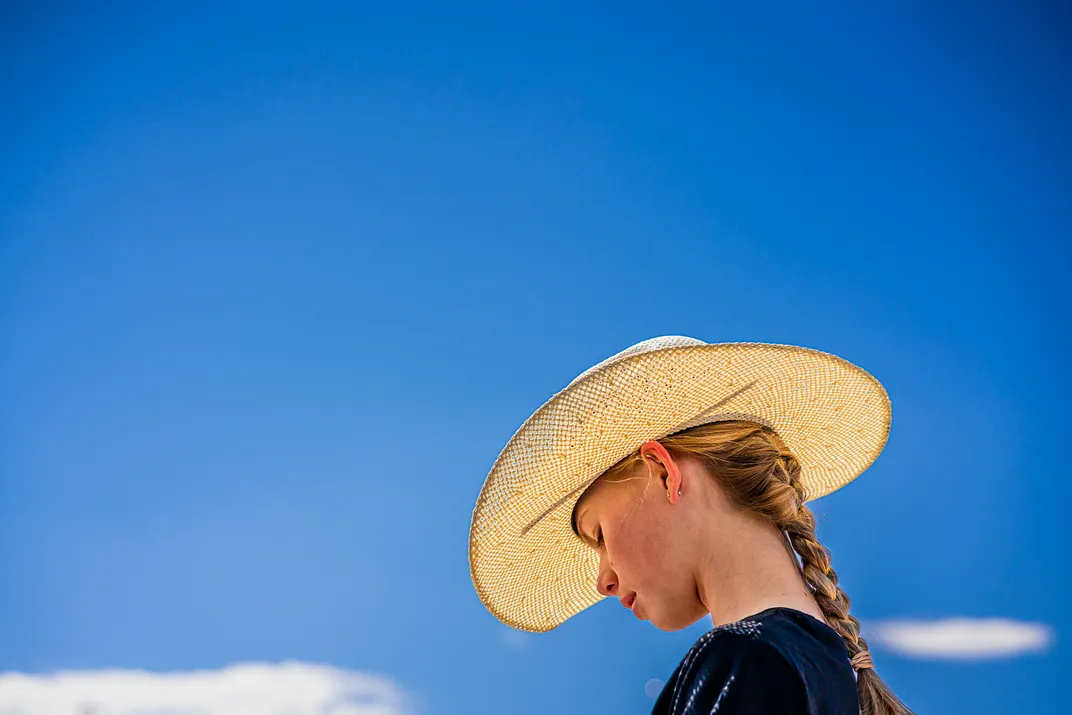 a person wears a cowboy cat against a blue sky