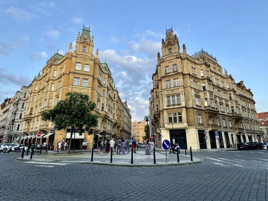 Two beautiful crenellated yellow buildings in Prague set against a bright blue sky.