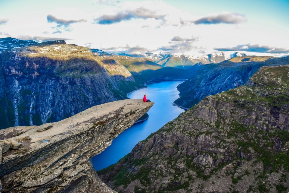 The girl sits on the edge of the cliff on the Trolltunga, Norway.