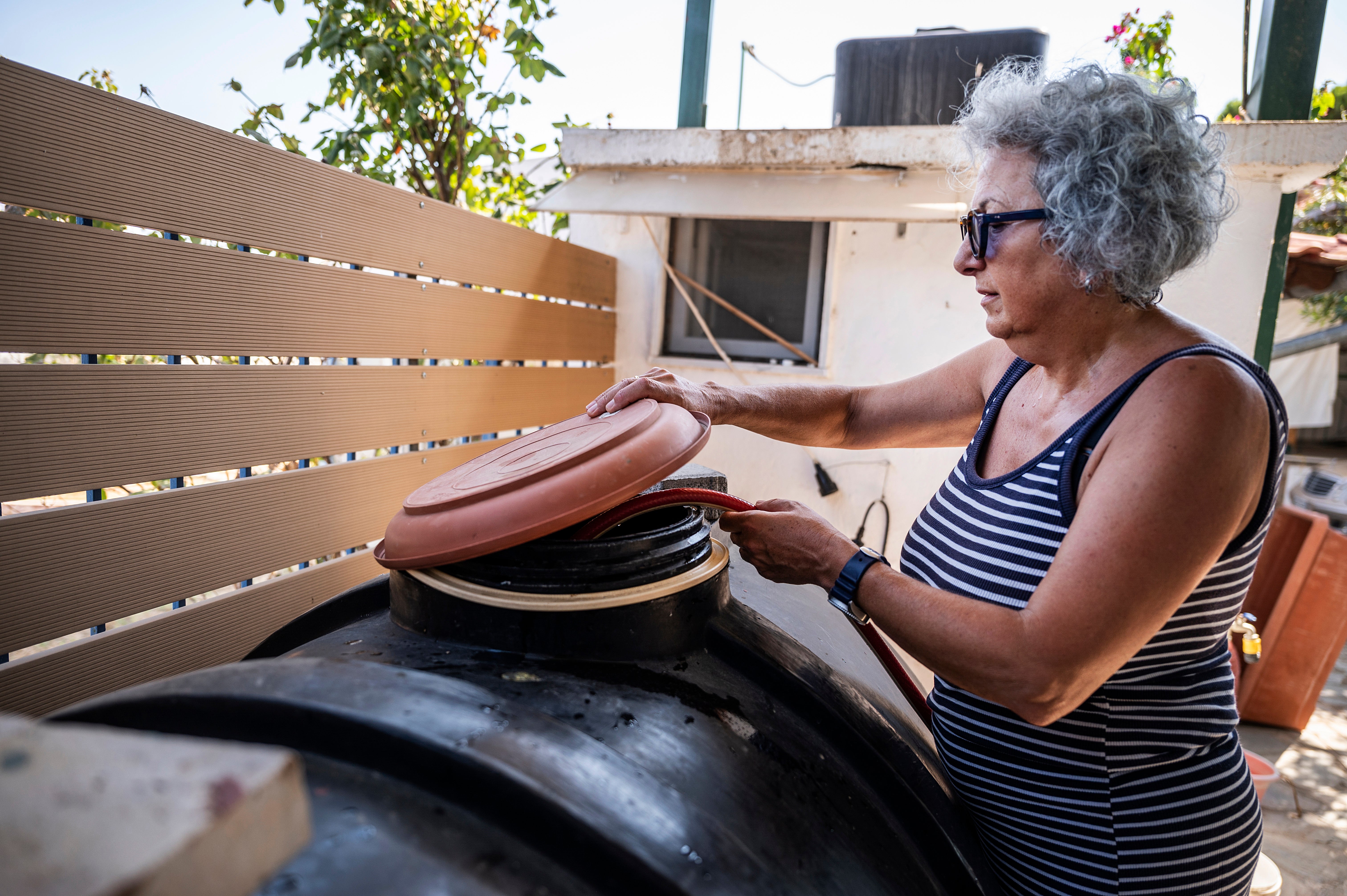 Haroula Psaropoulou, checks the level inside a water tank, in the village of Nea Potidea