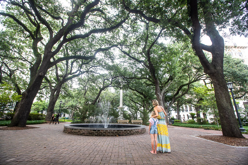 people standing next to trees and a water fountain