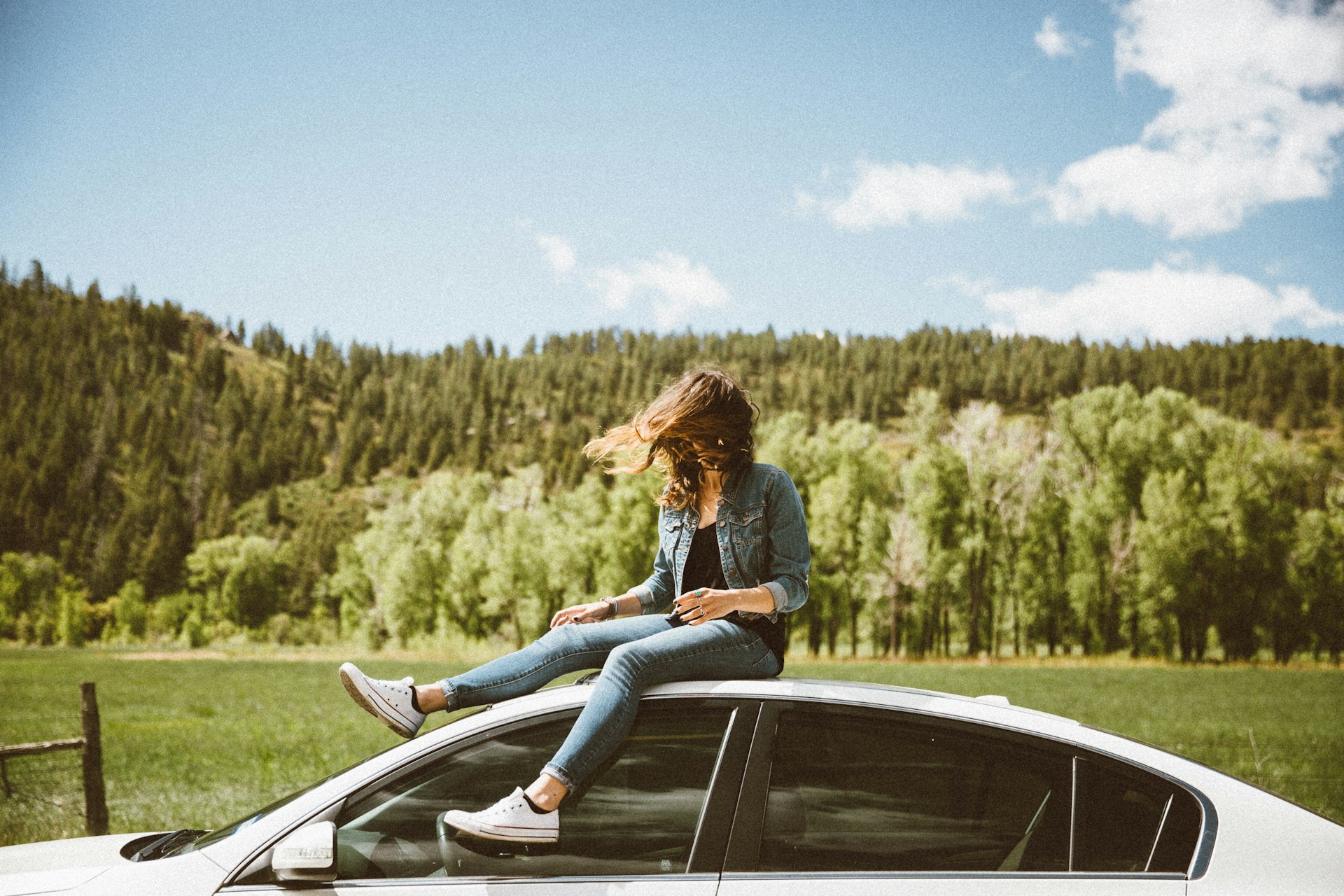 Woman sitting on a car during a road trip (photo: Averie Woodard).