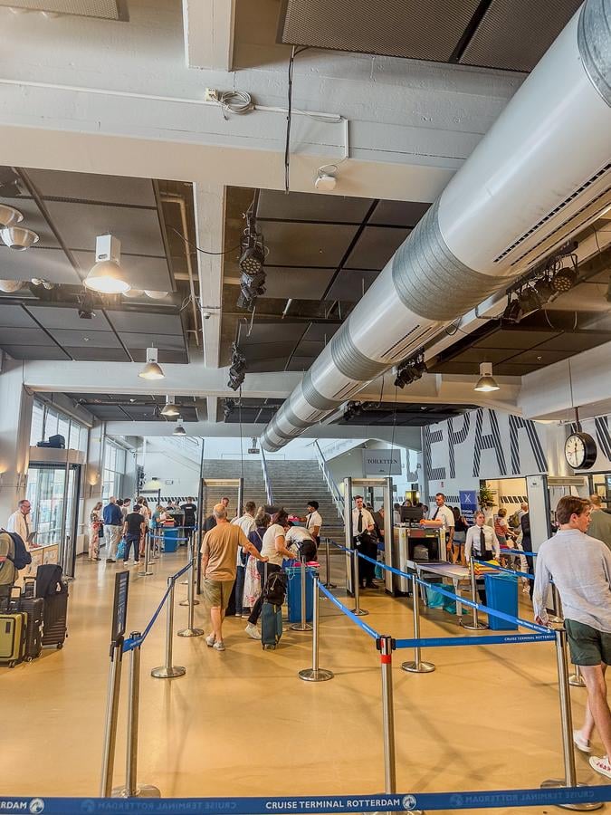 Security check at Rotterdam Cruise Terminal with passengers queuing and luggage for boarding.