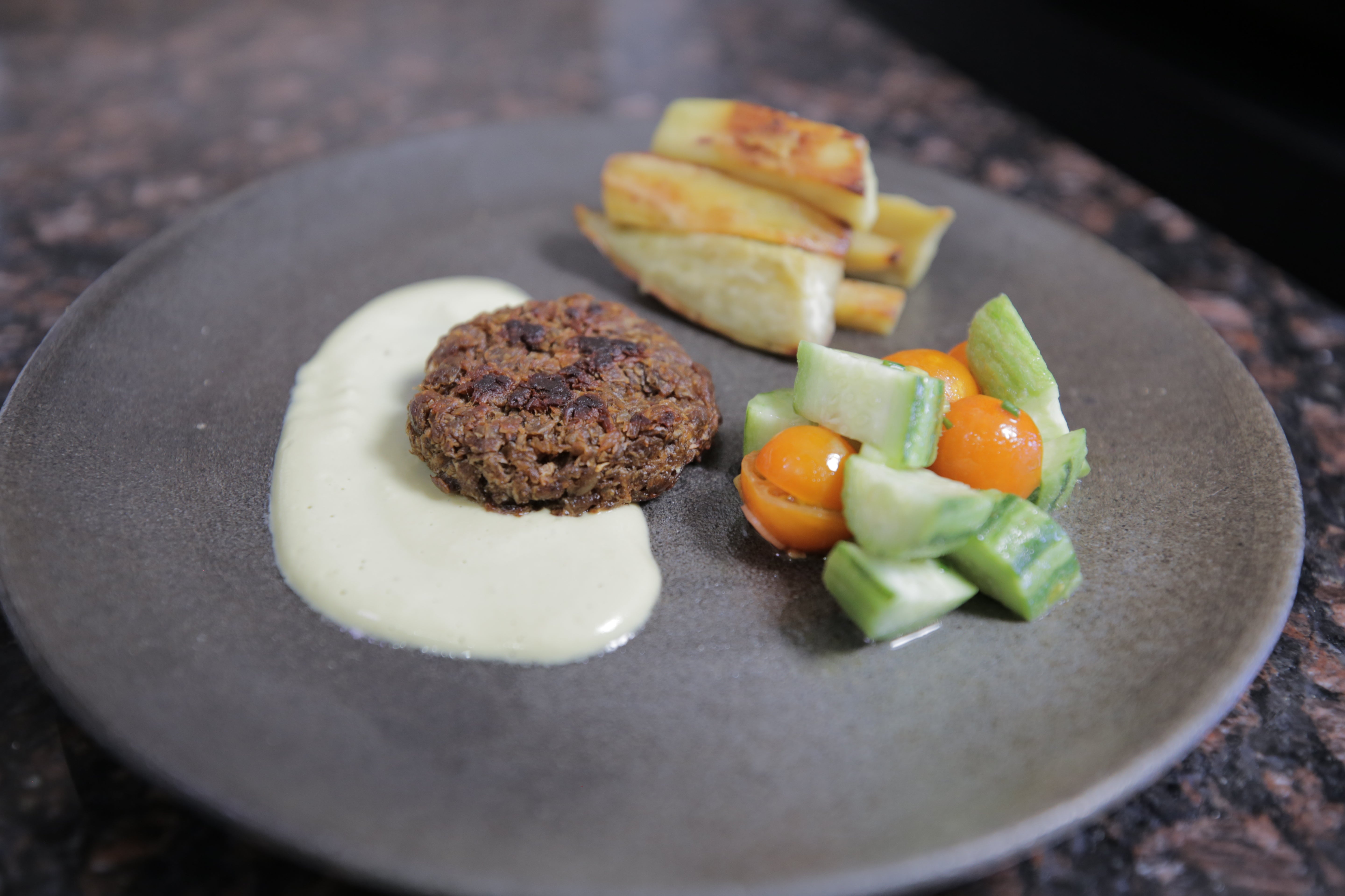 A sauteed patty composed of soy pulp innoculated with neurospora mould and left to ferment for several days. UC Berkeley postdoctoral fellow Vayu Hill-Maini prepared and cooked the patty, plating it with a cashew cream sauce, baked yams and a fresh cherry tomato and cucumber salad