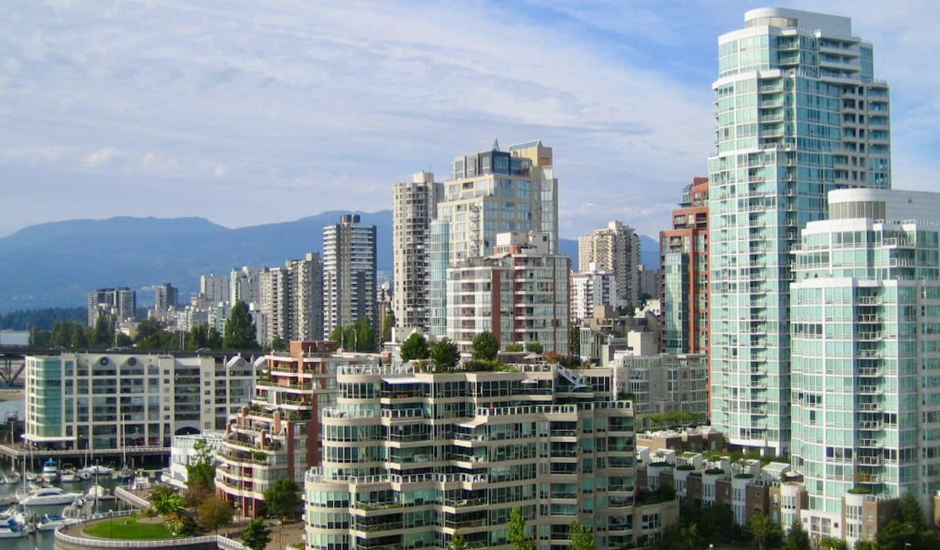 The towering skyline of Vancouver, Canada with mountains in the distance on a sunny summer day